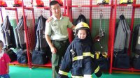 “我是小小消防員”主題活動(dòng)，小朋友們?cè)谙绬T叔叔的幫助下穿上消防衣。